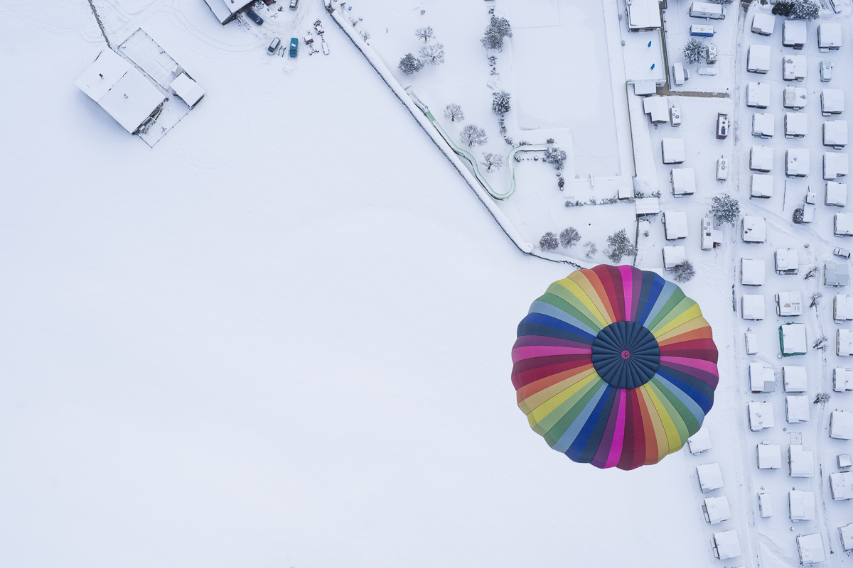 Survol d'un paysage enneigé et d'une montgolfière multicolore ©annejullien